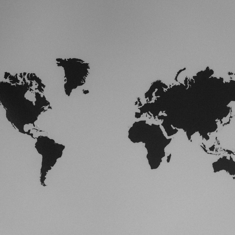 A simple black and white silhouette of a world map emphasizing continents against a stark background.